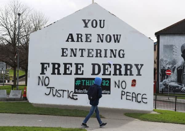 A young man walks past Free Derry Corner after fresh graffiti had been put on it following the PPS announcement