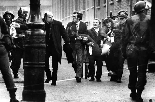 Bishop Daly with a wounded man on Bloody Sunday. Picture: Pacemaker