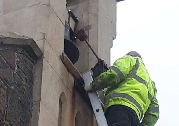 An engineer repositioning the bell hammer at St. John's Church, Glynn.