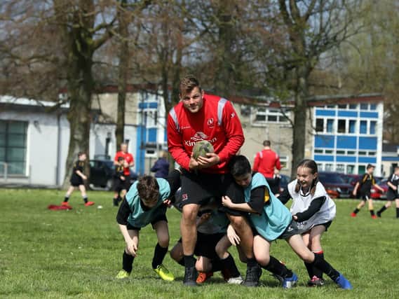 Ulster's Jordi Murphy fends off tackles from pupils at Edenderry Primary during a Kingspan Coaching Masterclass at the Portadown school