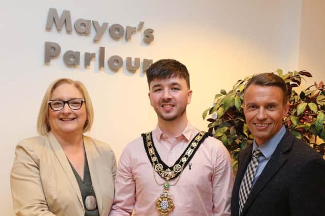 The new Mayor of Causeway Coast and Glens Borough Council, Cllr  Sean Bateson receives the chain of office from outgoing Mayor Councillor Brenda Chivers as Chief Executive David Jackson looks on.