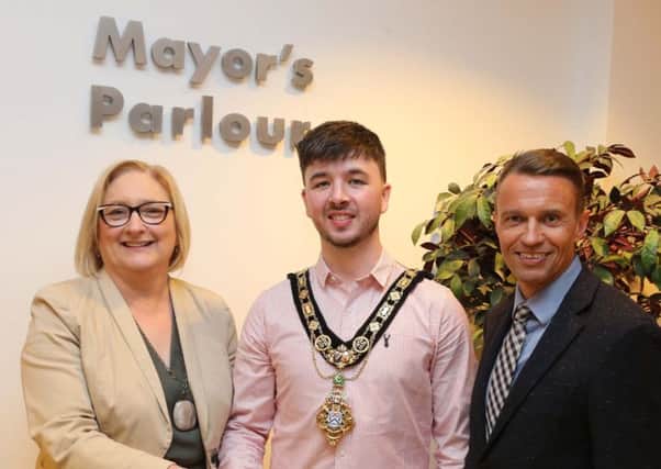The new Mayor of Causeway Coast and Glens Borough Council, Cllr  Sean Bateson receives the chain of office from outgoing Mayor Councillor Brenda Chivers as Chief Executive David Jackson looks on.