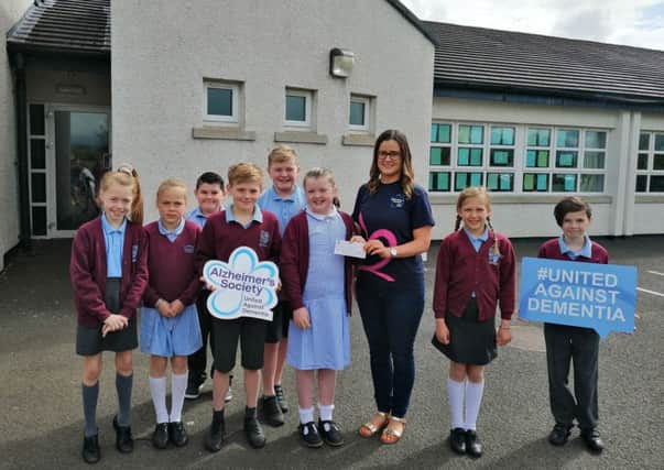 Children from Damhead PS presenting a cheque to Aoife McMaster of the Alzheimer's Society, the proceeds of a bake sale
