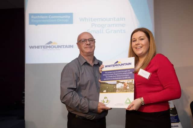 George Thompson from Rathfern Community Regeneration Group receives the funding award from Whitemountain's communications officer Niamh-Anne McNally.