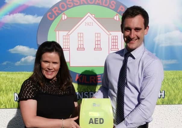 Mr Mullan taking receipt of the AED from Mrs Brenda Turner, daughter of Francis McWilliams