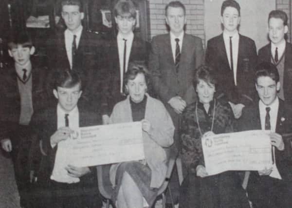 Receiving a cheque for £1,500 from the Cambridge House Boys' School on behalf of NI Hospice are Mrs Agarwala and Mrs Bloomer (seated front).  Presenting the cheque are class representatives and included is principal, WJ Wallace. 1989