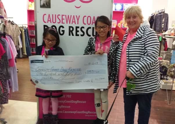 Yum Yum with her sister Yi Jean who raised £155 towards a heart operation for Susie. Yi Jean presented a cheque at the charitys shop in Coleraine to Chairman Maggie Dimsdale-Bobby with one of the rescue dogs Harry