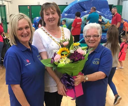 The Mayor, Cllr Maureen Morrow, presents Patricia McConnell, chairperson of Carnlough Community Association, with a bouquet of flowers , included is Joanne McIlhatton, programme co-ordinator.