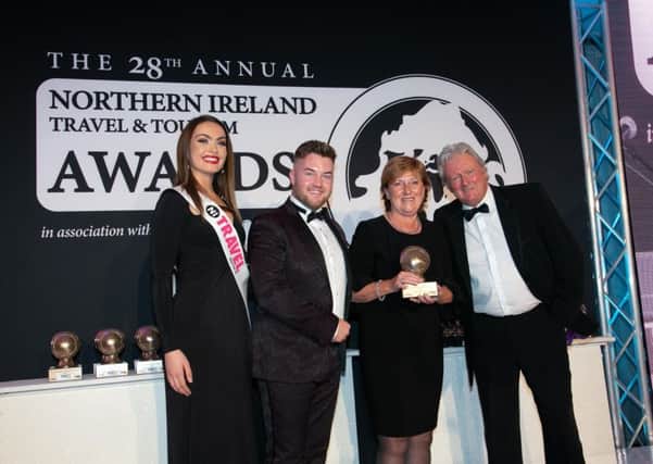 Wilma Erskine took home the NI Tourism Industry Awards 2019 at this year's Northern Ireland Travel and Tourism Awards, in association with Blue Insurance. She is pictured on stage receiving her award from Adam Bothwell of category sponsor Stena Line. Also pictured is host for the evening Charlie Lawson and ACA model Rachel Jones