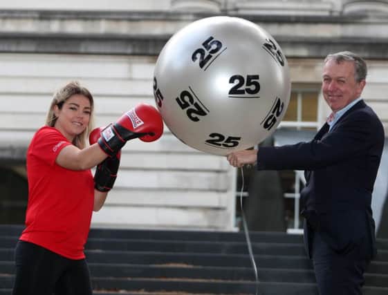 Paul Mullan, chair of the Northern Ireland National Lottery Distributors Forum, with National Lottery-funded youth worker Amy Stewart, from Monkstown Boxing Club, celebrate 25 knockout years of The National Lottery.