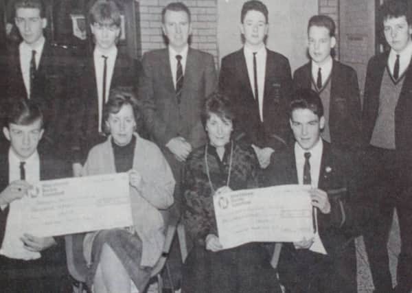 Receiving a cheque for £1,500 from the Cambridge House Boys' School on behalf of NI Hospice are Mrs Agarwala and Mrs Bloomer (seated front).  Presenting the cheque are class representatives and included is principal, WJ Wallace. 1989