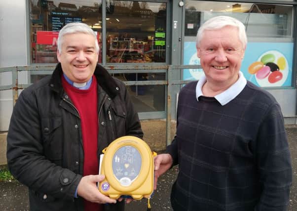Rev. James Boyd, rector of St Columbas, presents a defibrillator to Ian Hall, owner of Mace Supermarket, Moss Road