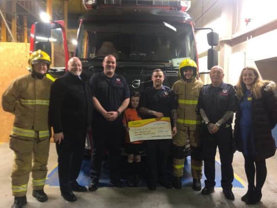 Stuart's father, David and son Jack join NIFRS colleagues to present a cheque to Friends of the Cancer Centre.
