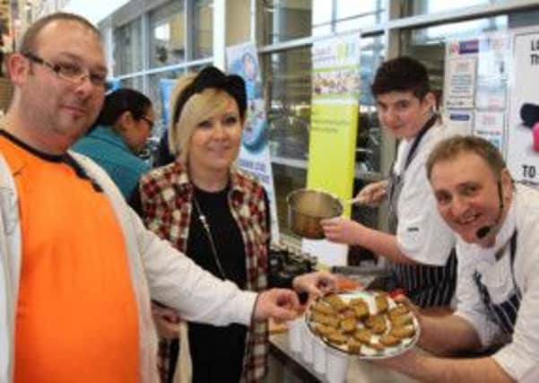 Gerry Faloona and Ciaran Mullan from Heaven's Kitchen serve up home made wheaten bread and soup to Kevin Greenan and Hannah McNeill from Lisburn during the "Give it a Go!" roadshow at Tesco's Craigavon. INLM1113-01