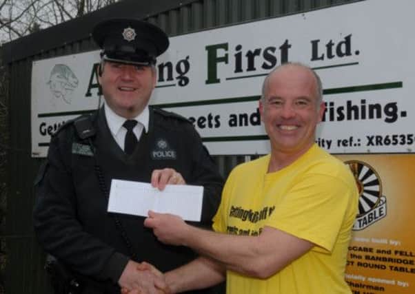Mark McGivern from Angling First receives a cheque for £200 from Const Alex Swan from the Dromore Neighbourhood Policing Unit. The money was provided to help Angling First continue with their work following theft of equipment from their premises. INBL0913-ANGLING1ST