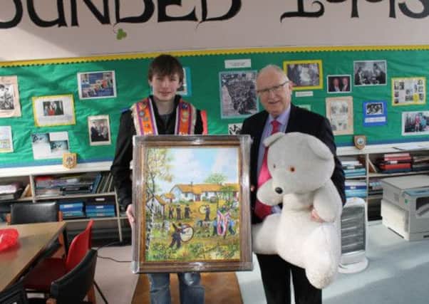 Artist Brendan McConville of the Buddy Bear Trust Conductive Education School presebts visitor Alastair McCracken of Magherabeg LOL 838 with a singed copy of The Gathering
