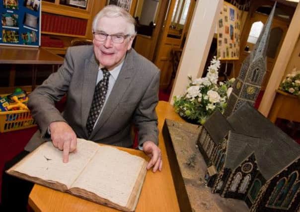 Sammy Malcolm who was taking tours of Shankill Parish Church on Saturday shows off the original parish record of baptisms, marriages, burials and vestry minutes, dating back to 1672. INLM19-700.