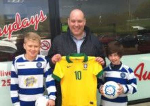 Frydays joint-owner Gerard O'Kane presents two Brazilian futsal balls to Northend United under-11 players Connor Meeke and Matthew Stewart.