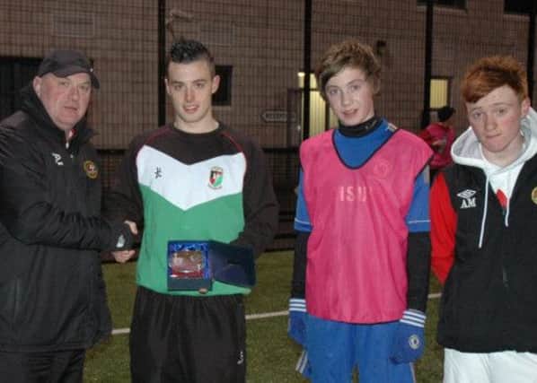 Carniny Youth Chairman Anthony McCartney presents a memento to former player Samuel McIlveen now Captain of Glentoran Seconds. U15 players Matthew Shevlin and Adam Mairs look on.