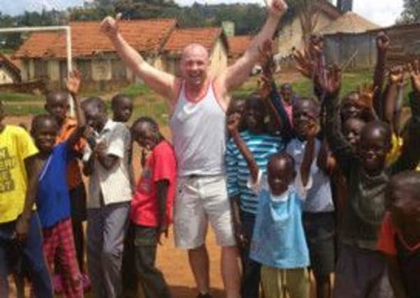 Lurgan man Karol Gallagher pictured in Uganda with children who are participating in his On the Ball initiative.