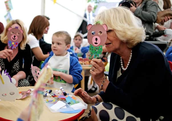The Duchess of Cornwall tries a cut out bear mask made by schoolchildren from Broughshane Primary School in Co.Antrim during her visit to the town. PRESS ASSOCIATION Photo. Picture date: Tuesday June 25, 2013. See PA story ROYAL Ulster. Photo credit should read: Julien Behal/PA Wire