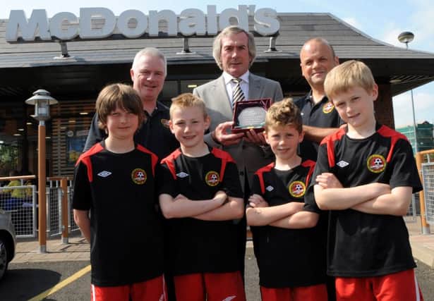 Pat Jennings presents the Regional IFA Accredited Club of the Year Award to Club Secretary, Billy O'Flaherty and Stephen Armstrong with some players from the club's  Under 10s.