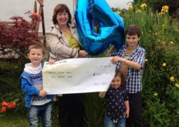 Archie Greer presenting a cheque for £600 to Sharon Gorman, donor development officer at N.I Hospice.  Pictured with Archie are his brothers Alfie (aged two) and Jamie (aged eight). INLT 27-603-CON