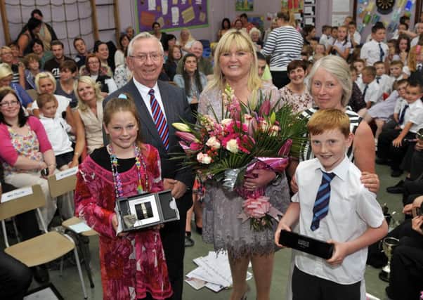 Mrs Linda Pillow, who is retiring from Dickson Primary School were she has been principal for the past nine years receives gifts at the final assembly from Mr Sam Gardiner, chair of the board of governors, Miss Mary Sergeant, vice principal and pupils Jessie Carson and Sophie Anderson. INLM27-105gc