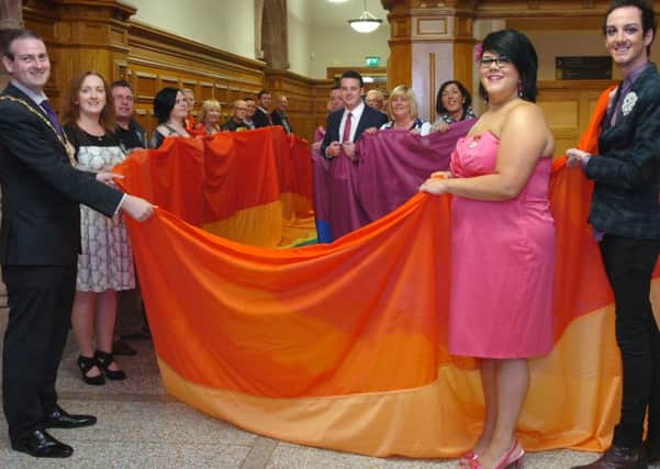 The Mayor Martin Reilly helps to unfurl the Foyle Pride rainbow banner with Amy Lame, special guest, Joe Carlin, chairperson, and people attending the launch of the event at the Guildhall. (DER3413PG038)