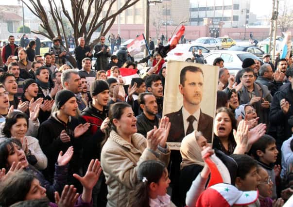 Pro-Syrian regime protesters chant slogans while one holds a picture of President Bashar Assad in the flashpoint city of Homs in central Syria, Thursday, Dec. 29, 2011.(AP Photo/ Bassem Tellawi)