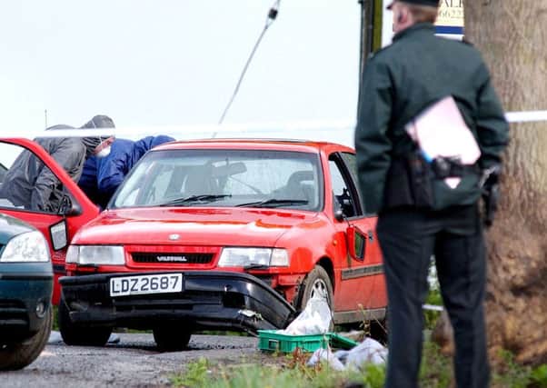 Alan Lewis - Photopress Belfast   4/10/07
Taken 30/4/03
Police forensic experts at the scene of the first fatal shooting by PSNI oficers in an operation at  Ballinderry Upper, near Lisburn, County Antrim. Police opened fire after trying to stop a red Vauxhall Cavalier (pictured) which struck two officers, the two men in the car were shot. 21 year old Neil John McConville from Bleary in Craigavon was shot dead, a second man was treated at Craigavon Area Hospital. A weapon was recovered from the car . The Police Ombudsman's Office investigated the shooting.
