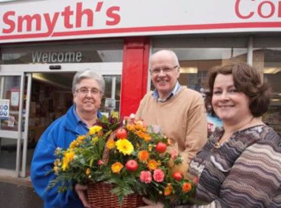 SAY IT WITH FLOWERS. Helen McCrellis (left), who has retired from Smyth's Linenhall St Spar, pictured on Friday receiving flowers from Debbie Stevenson and proprietor David Smyth.INBM41-13 023SC.