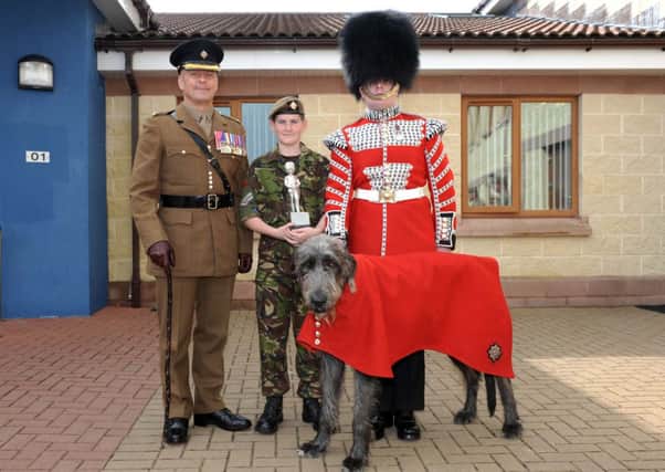 Cadet Lance Corporal Brandon Lynn pictured receiving his commemorative trophy from Major Simon Nicholls MBE representing the 1st Battalion Irish Guards.  Pictured alongside is the character the Cadets thought stole the show: Domnhall, the Irish Guards Wolfhound mascot with dog-handler, Drummer David Steed.