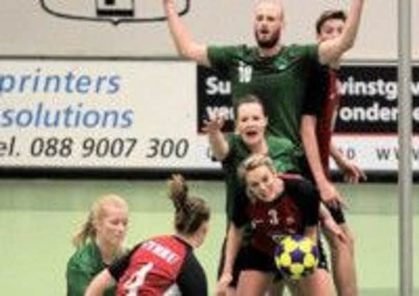 Jane, in green with her right arm outstretched, blocks a Welsh player.