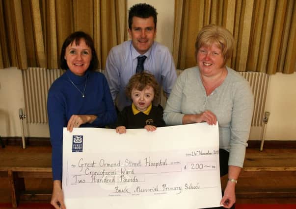 Buick Memorial PS pupil Jessica Philpot, along with principal Mr. R. White, teacher Mrs. J. McCluggage and classroom assistant Mrs. G. Glover, are pictured with a cheque for £200 for the Great Ormond Street Hospital, Craniofacial Unit, that was raised from the schools annual harvest service. INBT47-208AC