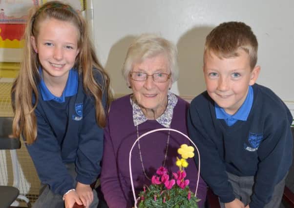 Flowers were presented to former pupil Lilian Sturdy by Leah Cambridge and Kurtis Forsythe after a talk she gave during the Mullaghdubh Primary School 100th birthday celebrations. INLT 46-306-PR