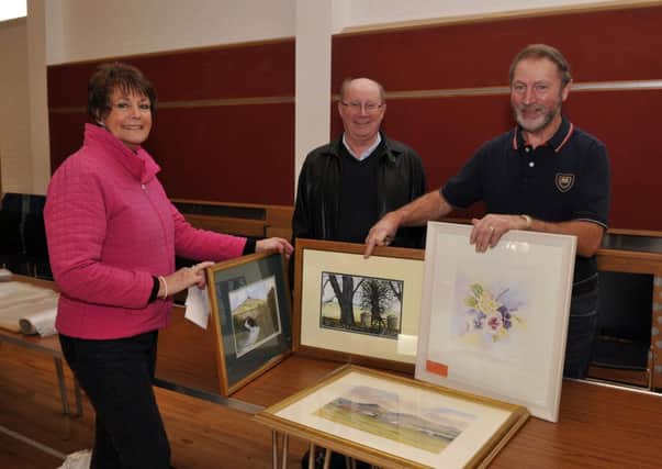 Colin McLoughln, right, organiser of the art exhibition and sale at Magheralin Parish Church Hall, receives entries from Lindsay and Keith Emerson. INLM47-128gc