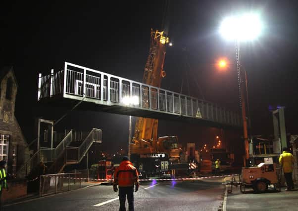 The parapet of the bridge is lifted by the crane and swung towards the ground.
