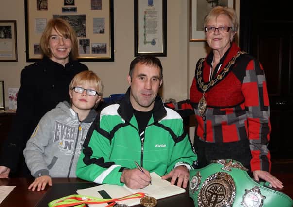WKC World kick-boxing champion Gary Dickson signs the visitors book at a reception in the Mayor's Parlour for members of the Northern Ireland Kick Boxing team who have just returned from the World Championships in Taranto, Italy. Included is Gary's son Niall, his wife Denise and Mayor of Ballymena Cllr Audrey Wales. INBT 49-172CS