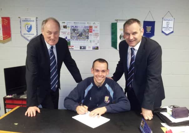 Tony Kane signs a two-year contract extension at Ballymena United, watched by vice-chairman John Taggart and manager Glenn Ferguson.