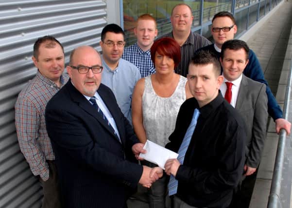 Ronnie McDowell, Ballymena United Management Committee, receives a cheque from Johnny Russell and members of the Paradise Supporters Club.