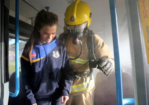 A member of the NIFRS team assists casualty Sinead Cottrell, Year 14 St Killians College from Glenarm, off the bus. INBM50-13