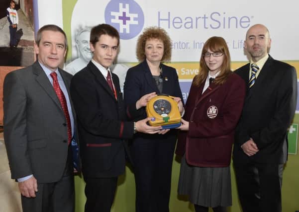Carrickfergus Grammar School pupils, Ryan Yeung and Sarah Patterson, with school representative Mr Lyons, receive their defibrillator from Sports Minister Carál Ni Chuilín and Declan OMahoney, Chief Executive of defibrillator manufacturer, HeartSine Technologies, at a special ceremony in Stormont.  INCT 51-720-CON
