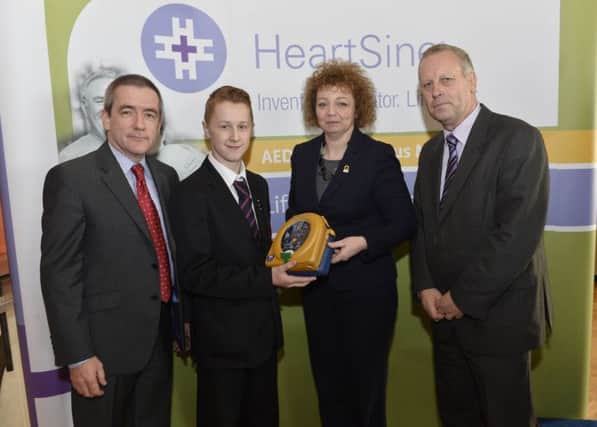 Dunluce School pupil, Isaac Malcolm, and school representative, Mr Loughrey, receive their defibrillator from Sports Minister Carál Ni Chuilín and Declan OMahoney, Chief Executive of defibrillator manufacturer, HeartSine Technologies, at a special ceremony in Stormont.