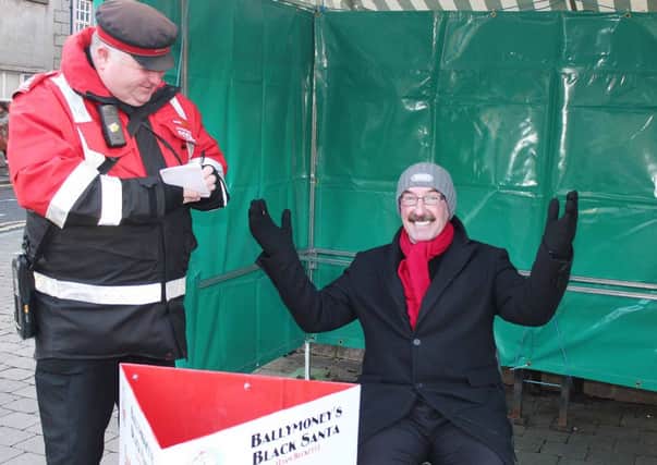 YOU'RE BOOKED...Local traffic warden Ian Leighton gets his book out to Ballymoney's Black Santa (Liam Beckett). Soccer commentator Liam is in his sixth year of the  Black Santa sit-out to raise money for local charities. INBM51-13 F