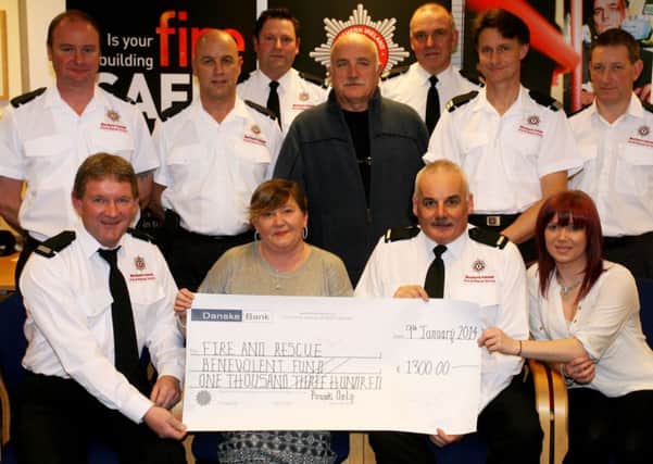 Siobhan Shiels and Tamara Sheils present a cheque for £1300, money raised from a pub quiz night, to Fire Fighters Sam McConkey and Ian Courtney for the Fire and Rescue Benevolent Fund. The cheque was presented in memory of Siobhan's daughter who tragically in a house fire 20 years ago. Fire fighters McConkey and Courtney, along with FF Chris McGaffin (pictured back row) where among the fire fighters who attended the scene 20 years ago. Also included is members of White Watch, Ballymena. INBT03-213AC