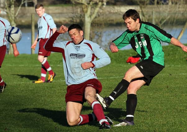 Newbuildings  Reserves defender Daryl Wallace, goes in with a tackle on Dungivens Emmett OKane,  during their City Cup game at the Prehen Playing Fields.  INLS 0314-531MT.