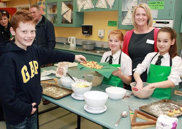 Miss McBride of St Patrick's College watch on as visitor Thomas helps himself to some buns baked in Home Economics during the open night by year 8 pupils Maria and Daria. INBT 04-811H
