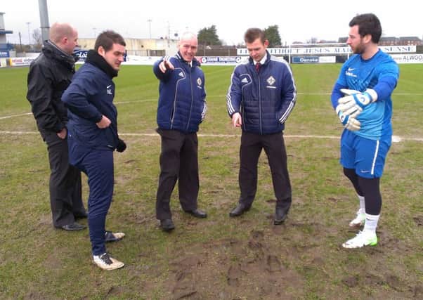 Referee Tim Marshall inspects the pitch.