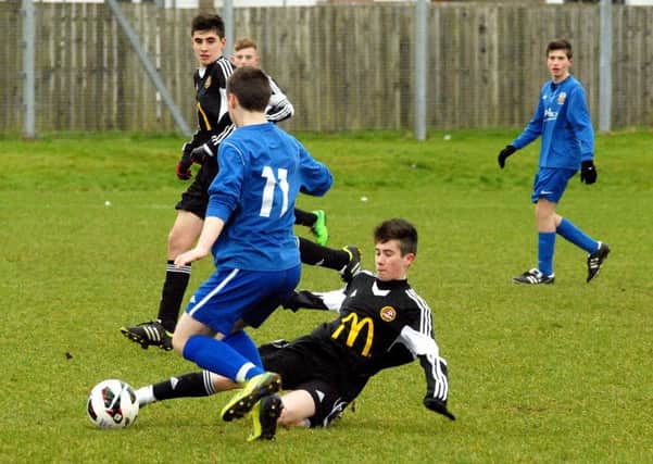 A Carniny Youth under-15 player makes a full-length sliding tackle during Saturday's game against Glenavon. INBT 06-902H